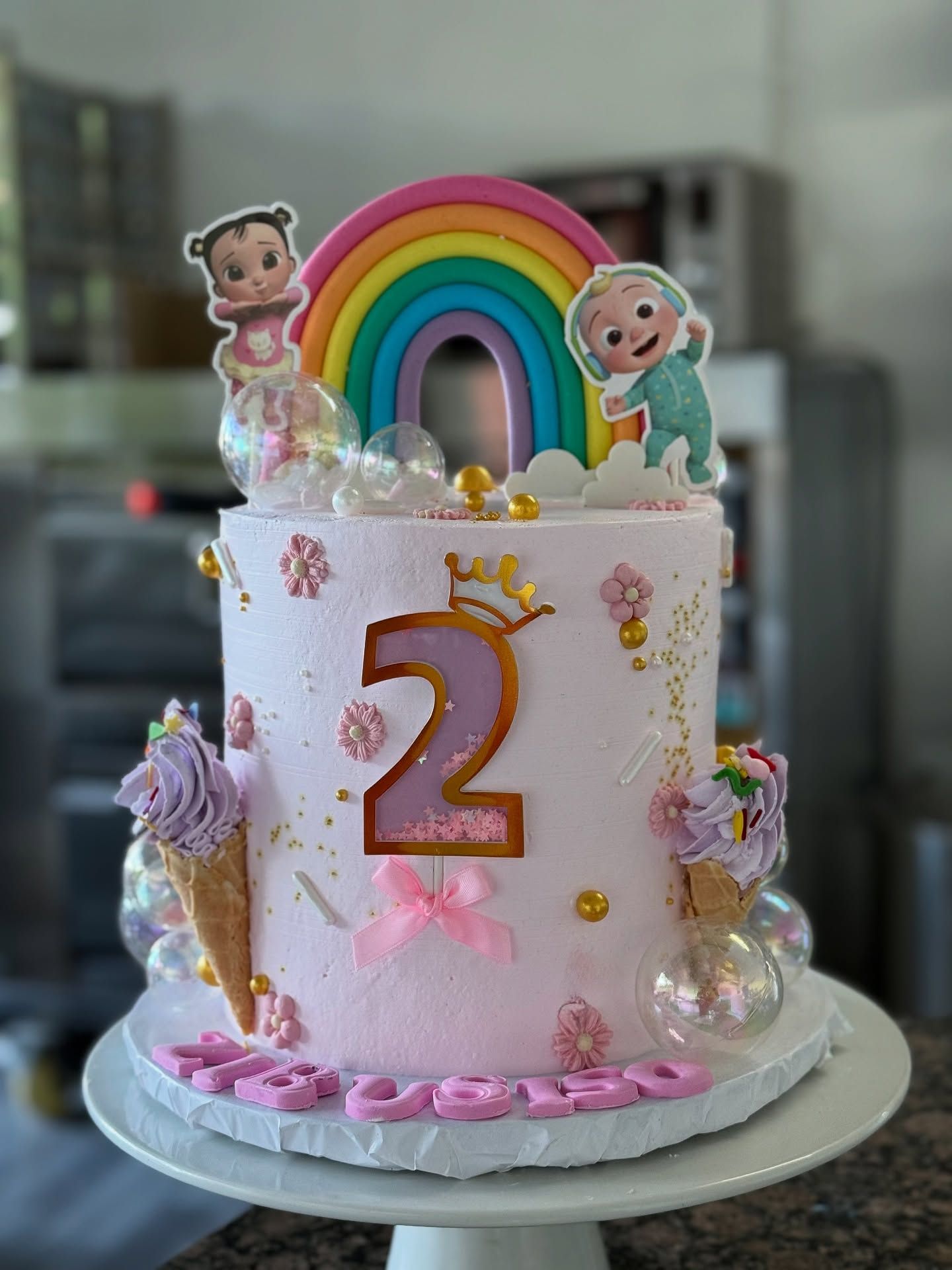 A pink two-tier rainbow celebration cake by b·treats